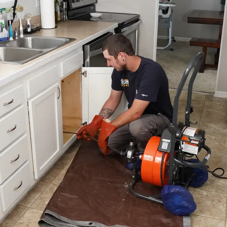 Plumber with plumbing equipment inspection under a kitchen sink