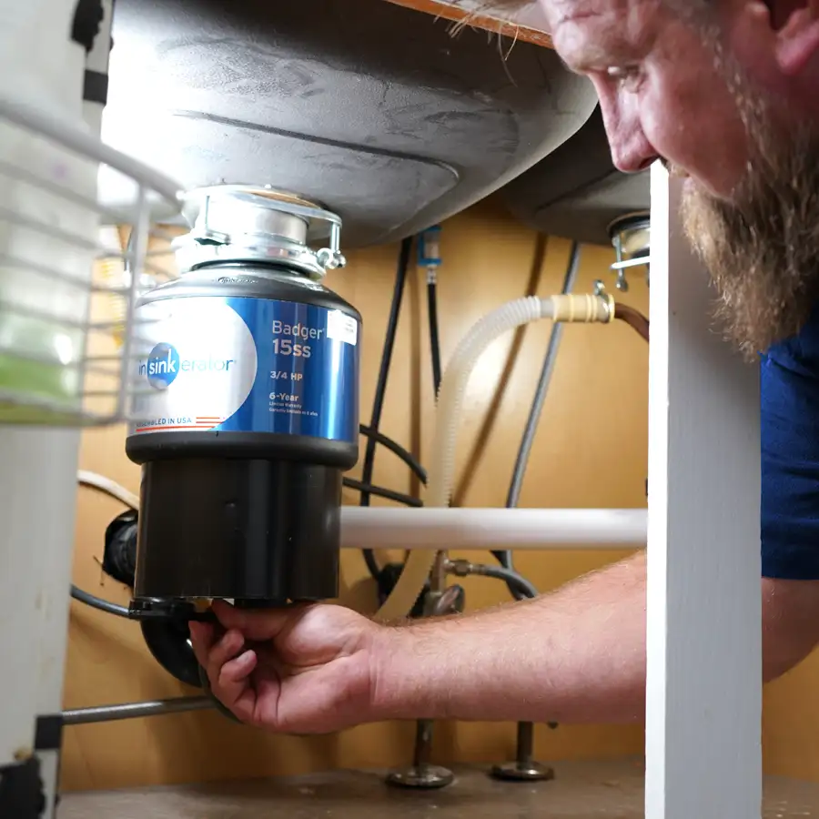 Plumber adjusting a setting on a garbage disposal under a sink