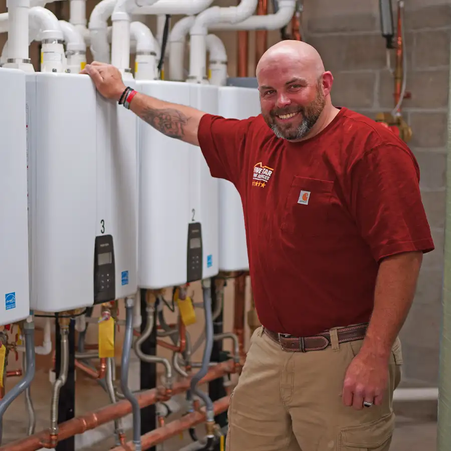 Plumber leaning next to 4 tankless water heaters