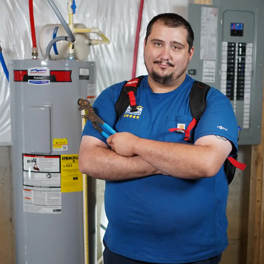 Plumber holding a wrench next to a water heater