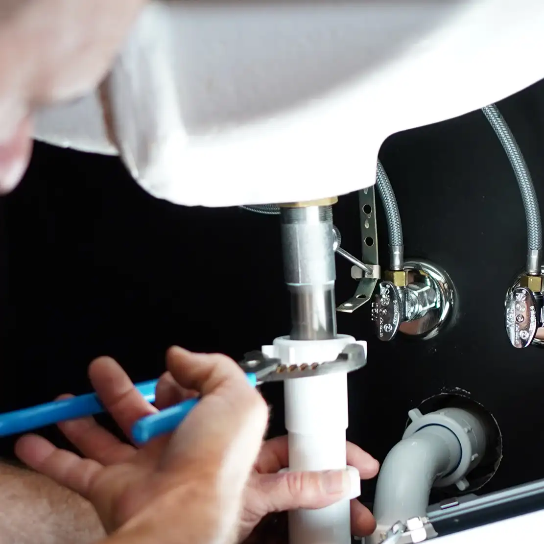 Plumber with a wrench fixing a bathroom sink