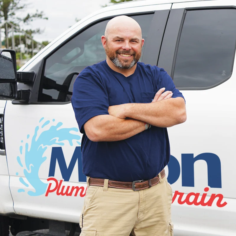 Plumber standing in front of a truck with crossed arms