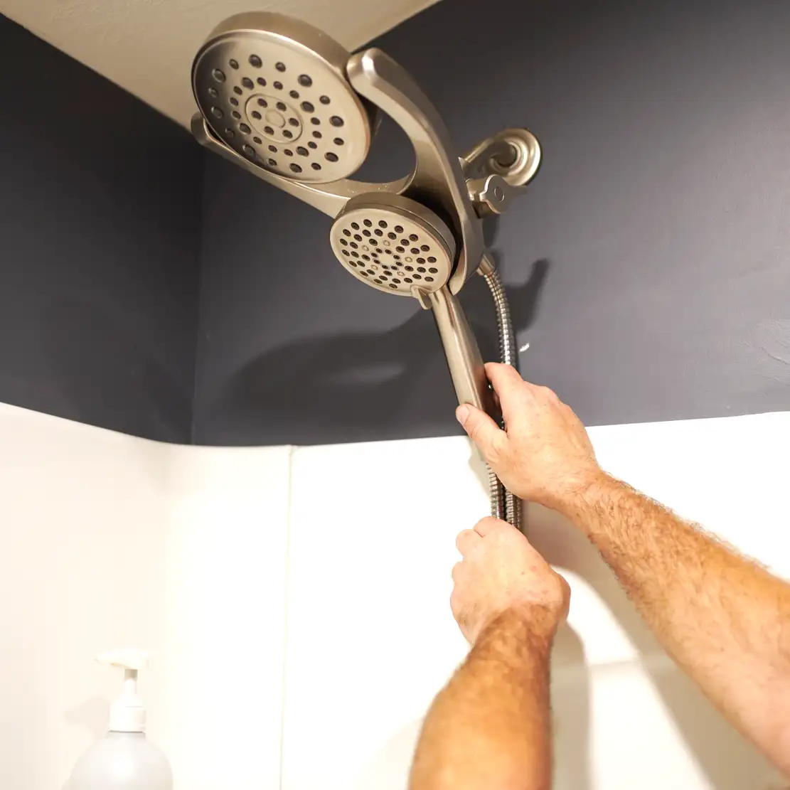 Close up of hands inspecting a shower head in the bathroom