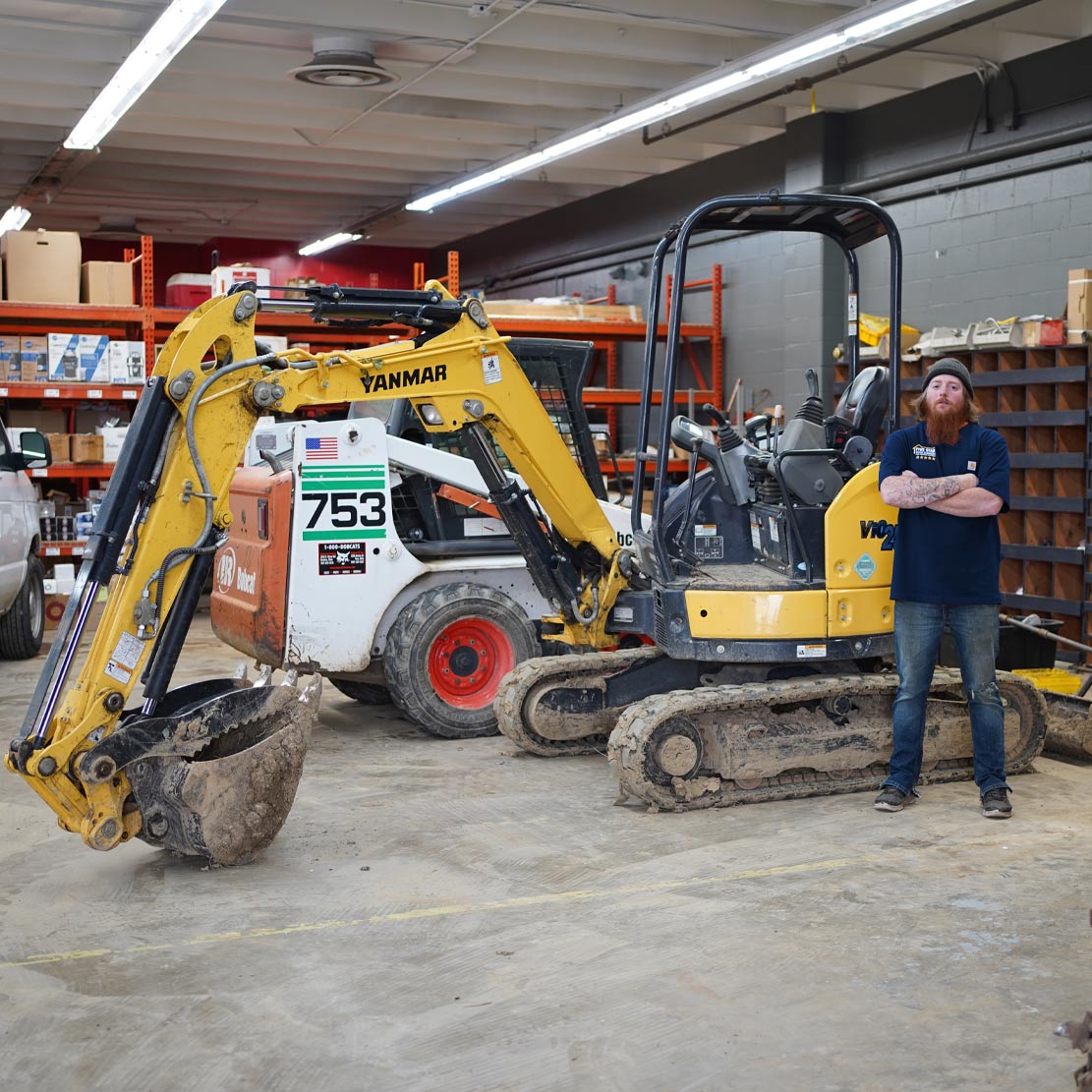 Plumber next to a excavator in a garage