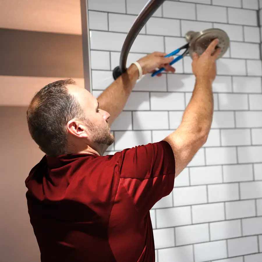 Plumber fixing a shower head with a wrench