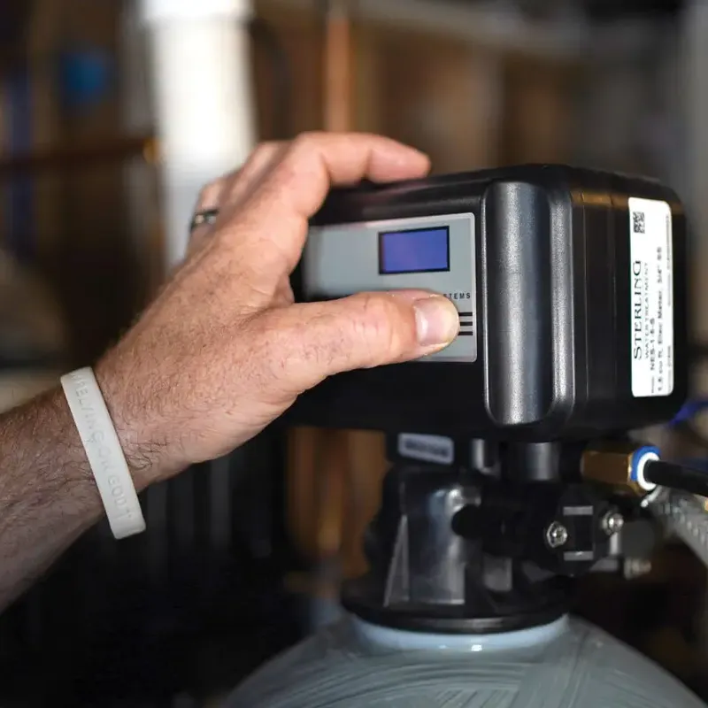 Close up of a hand operating a water softener