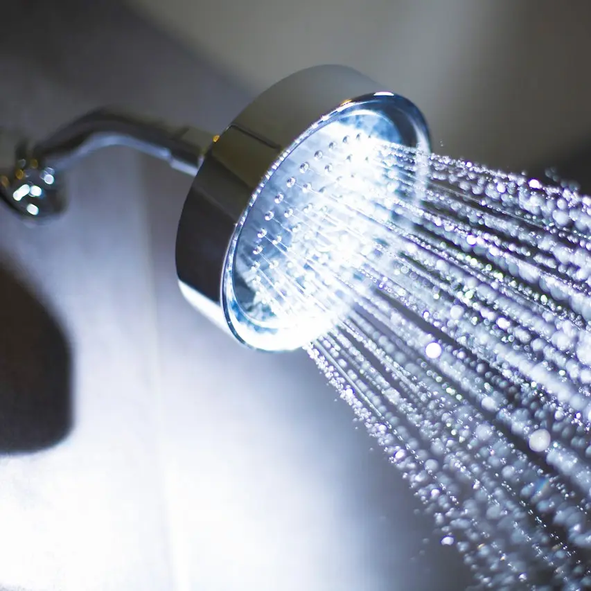 Close up a shower head that is on with water streaming