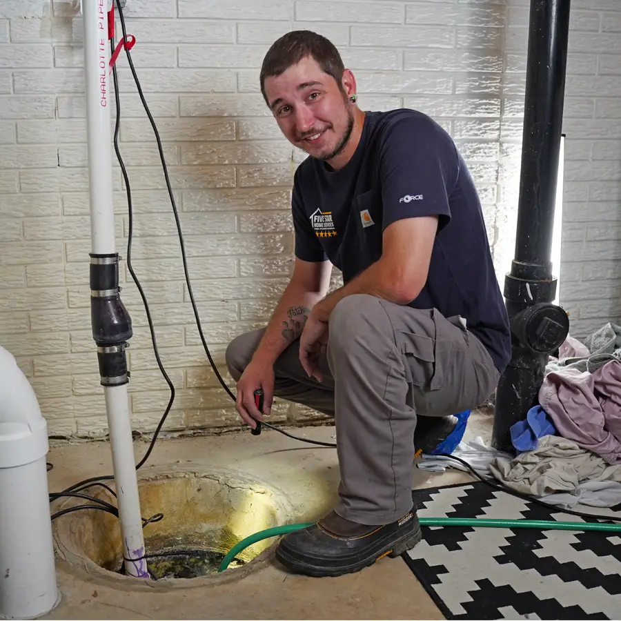 Plumber kneeling next to a sump pump with a flashlight