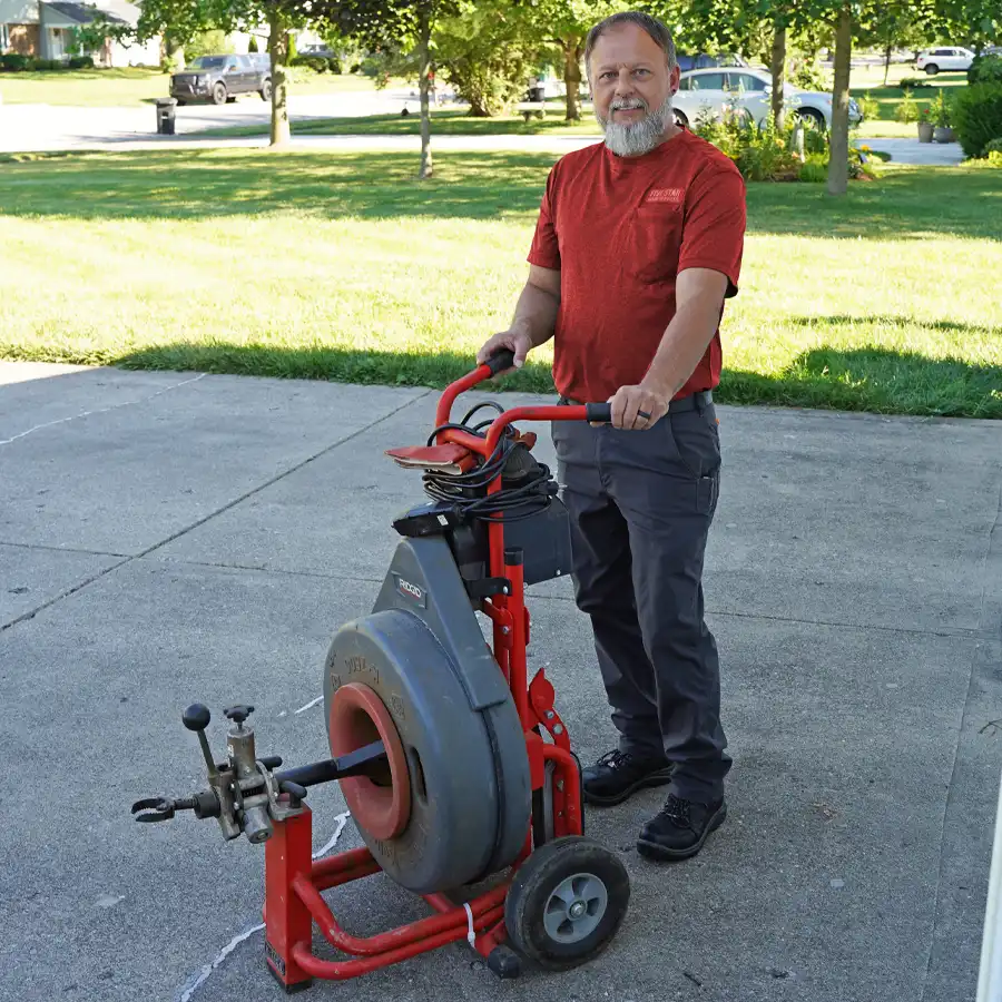 Plumbing standling next to a plumbing video camera inspection machine