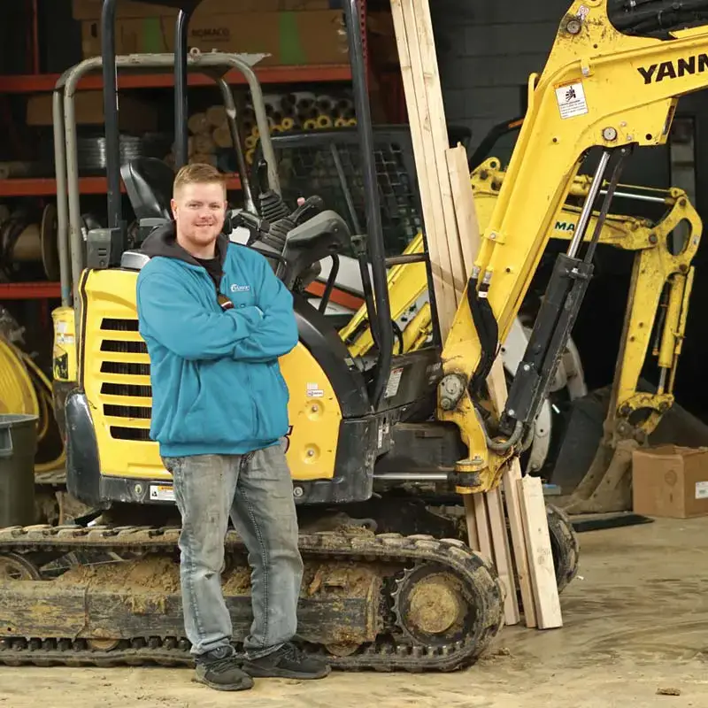 Plumber standing next to an excavator